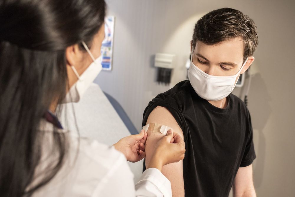 boy getting bandage on arm after receiving vaccine
