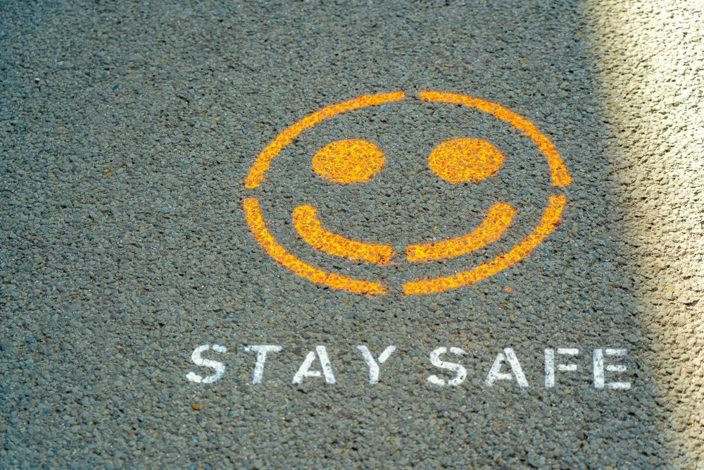 The words "Stay Safe" spray painted on the sidewalk with a happy face
