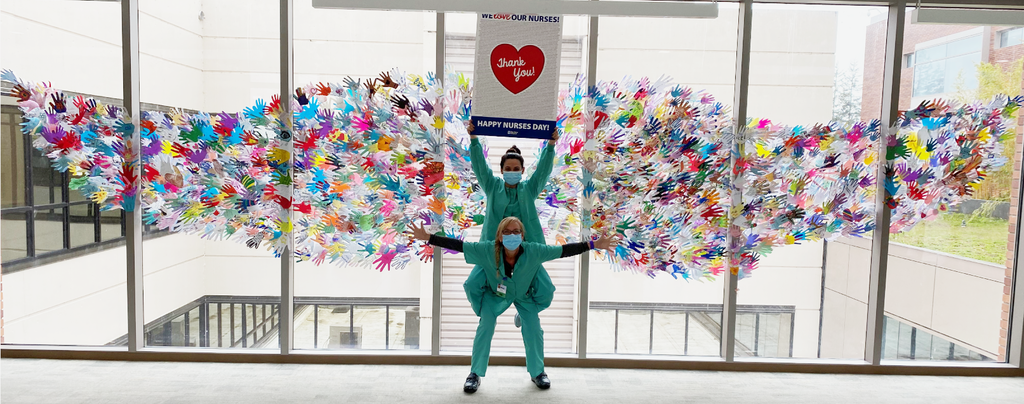 children's hand art displayed in a hospital window in the shape of wings, hospital staff in center of wings